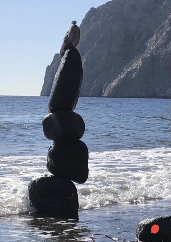 Red dot visits Nino’s Stack of stones on Santorini by Bill Walker